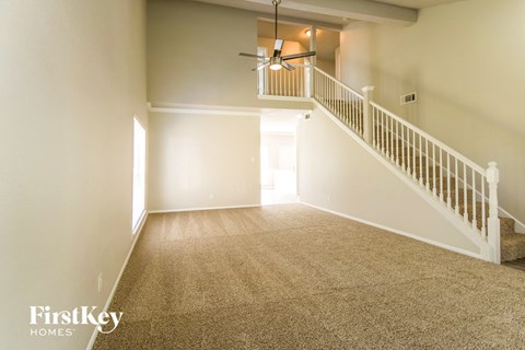 A spacious room with a staircase and a ceiling fan.