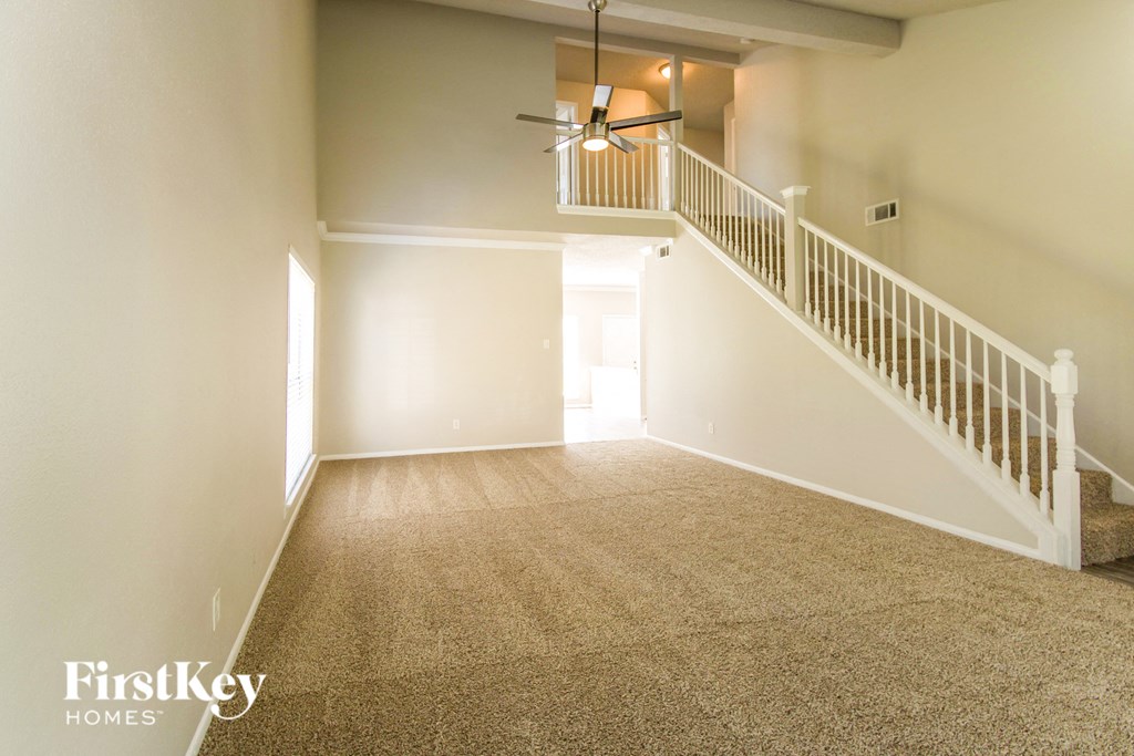 A spacious room with a staircase and a ceiling fan.