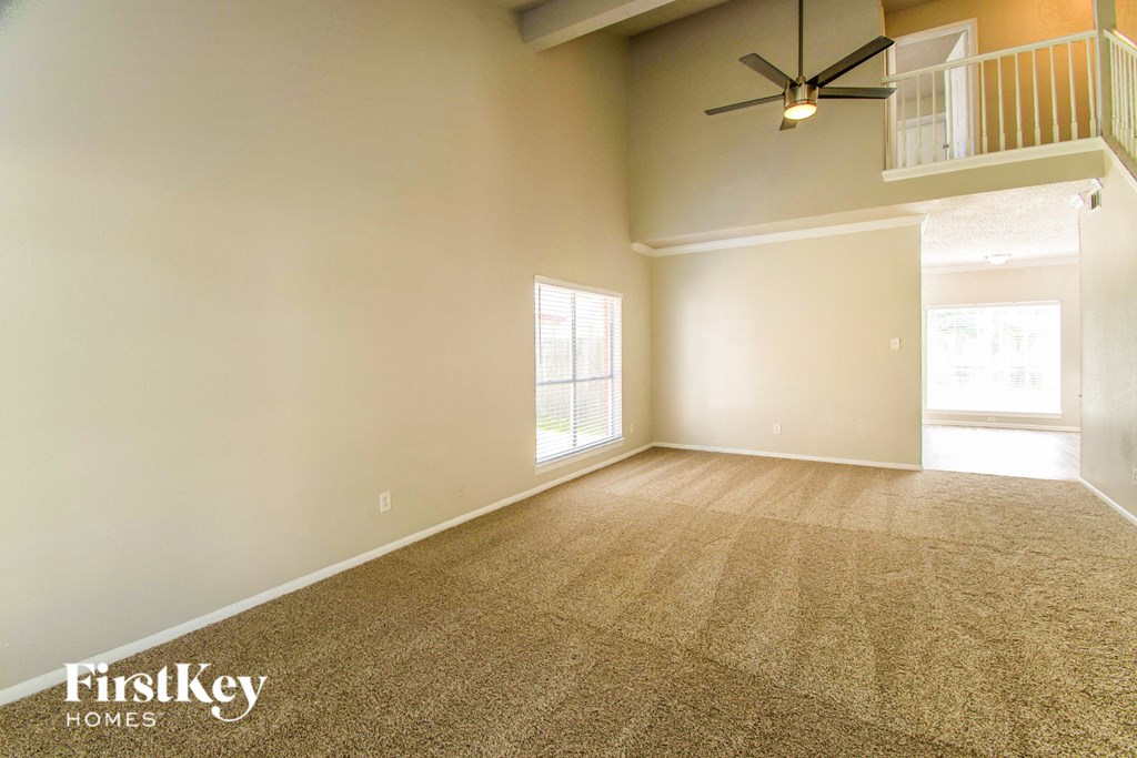 A room with a carpet floor and a ceiling fan.