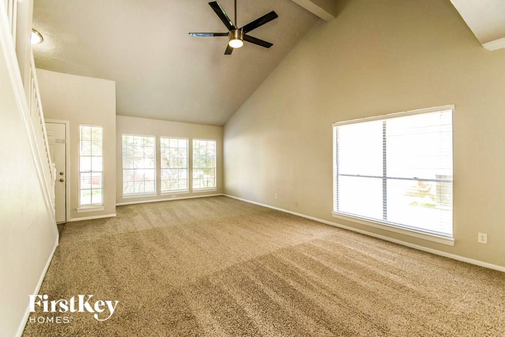 A spacious room with a ceiling fan and large windows.