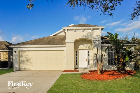 A house with a garage and a tree in front.
