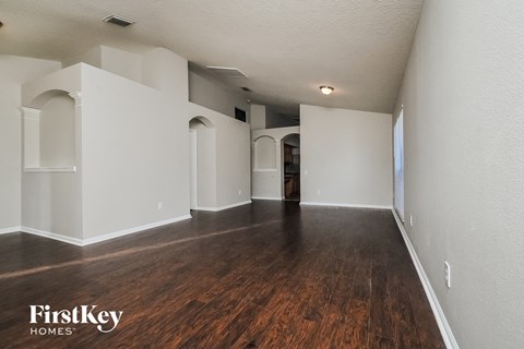 A spacious room with wooden floors and white walls, with a FirstKey Homes logo in the corner.