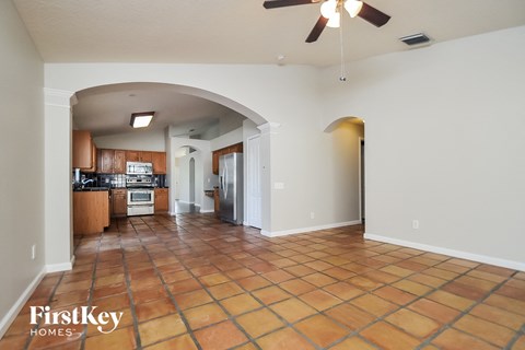 A spacious kitchen and living room with a tile floor and a ceiling fan.