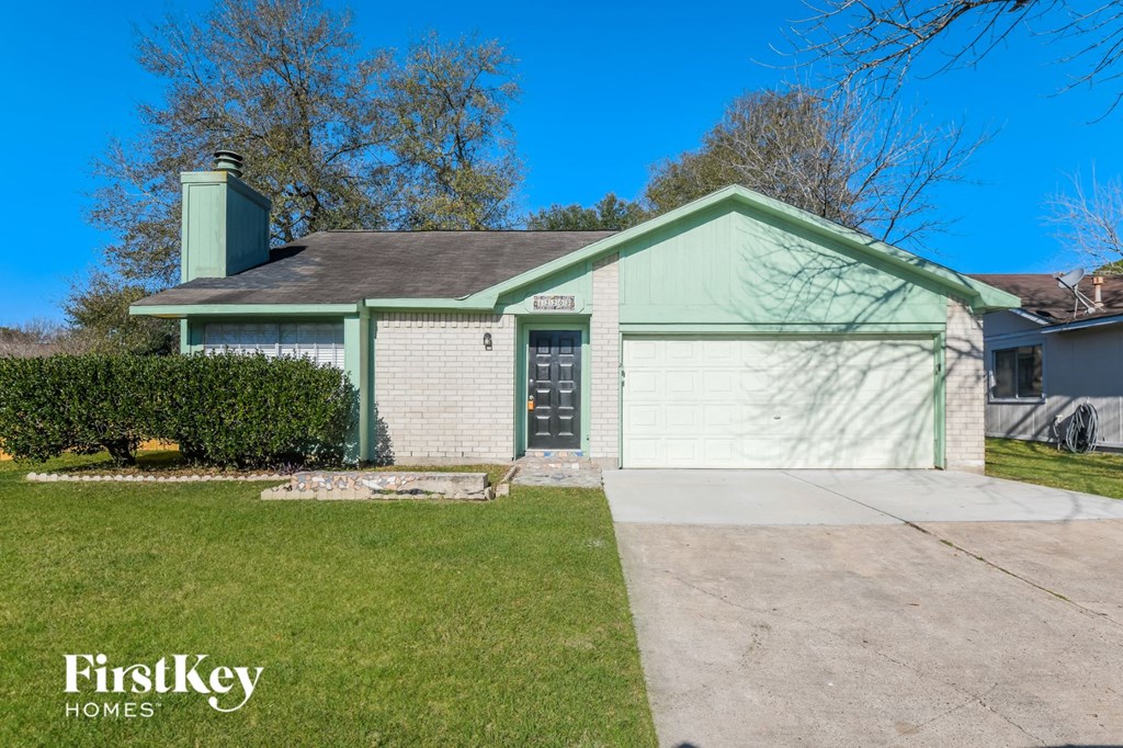 a green and white house with a driveway and a green garage door