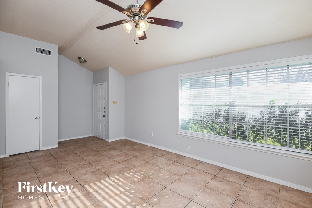 a living room with a large window and a ceiling fan