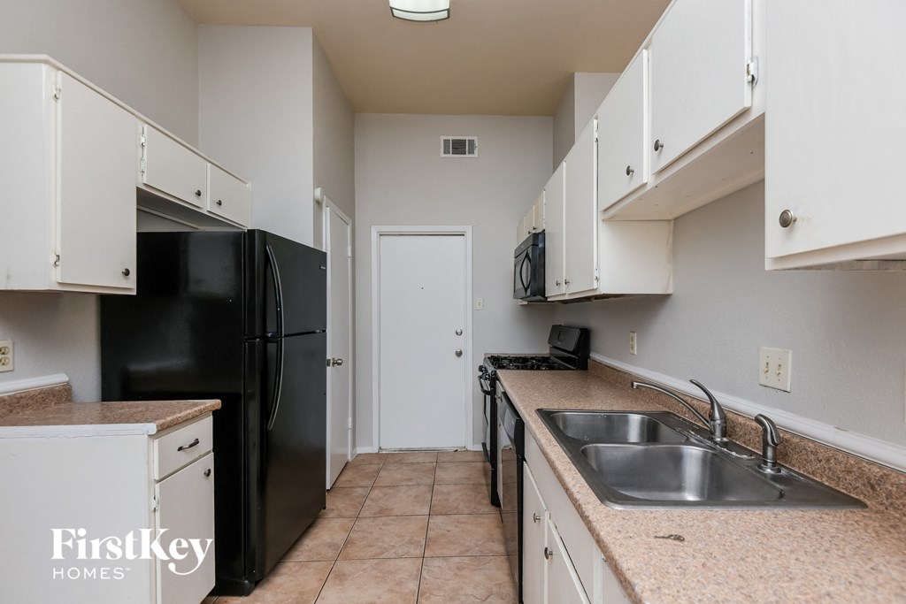 a kitchen with white cabinets and a black refrigerator