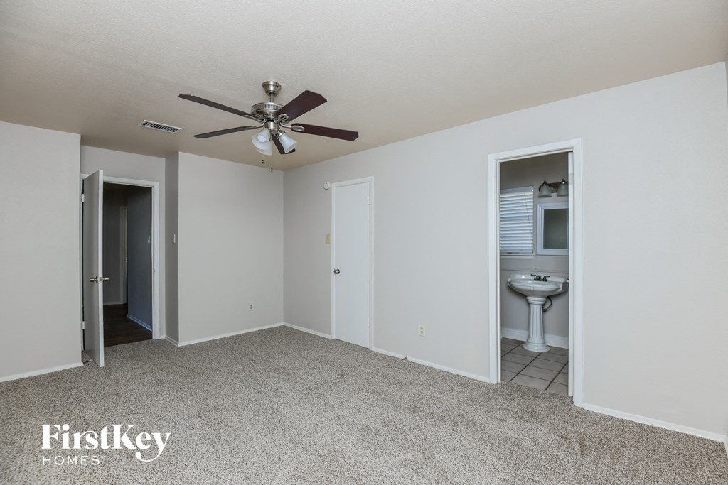 a bedroom with a ceiling fan and a bathroom