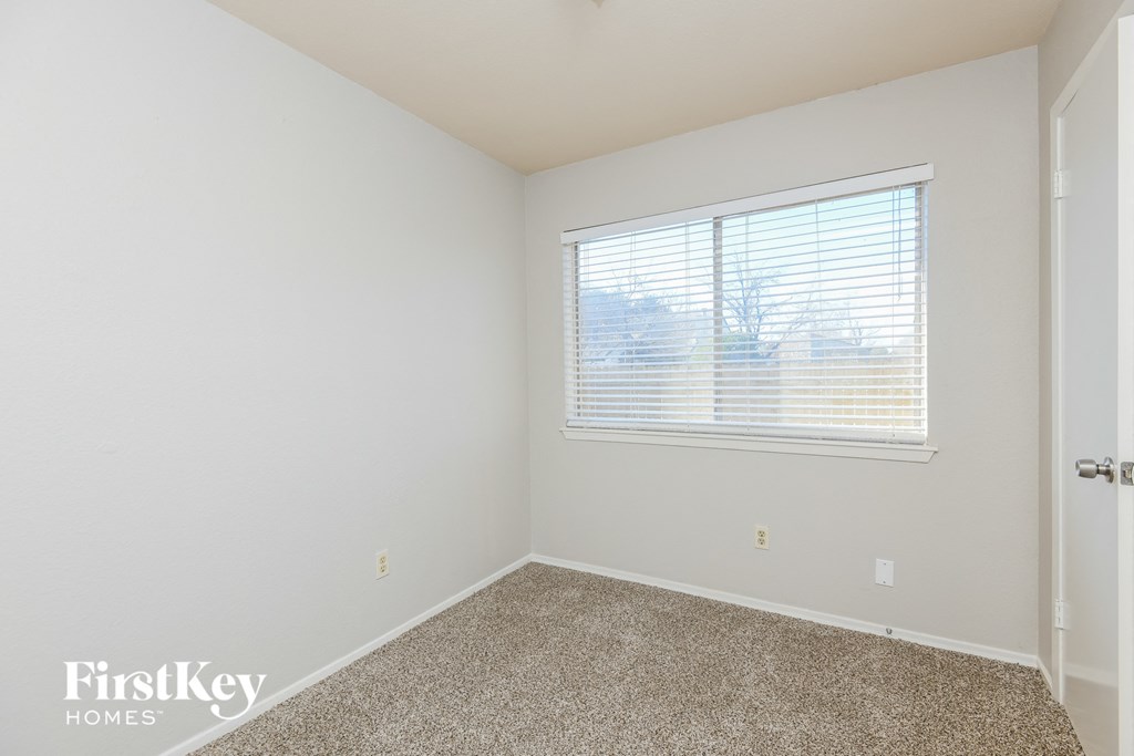 a bedroom with a window and a carpeted floor