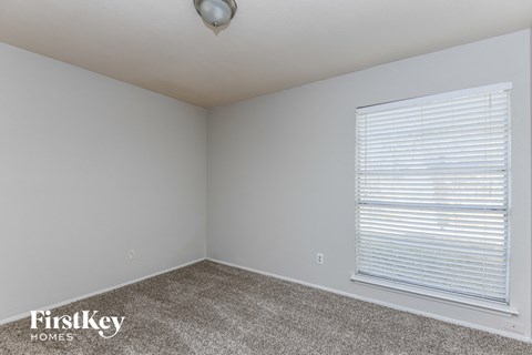 the living room of an apartment with a large window and carpet