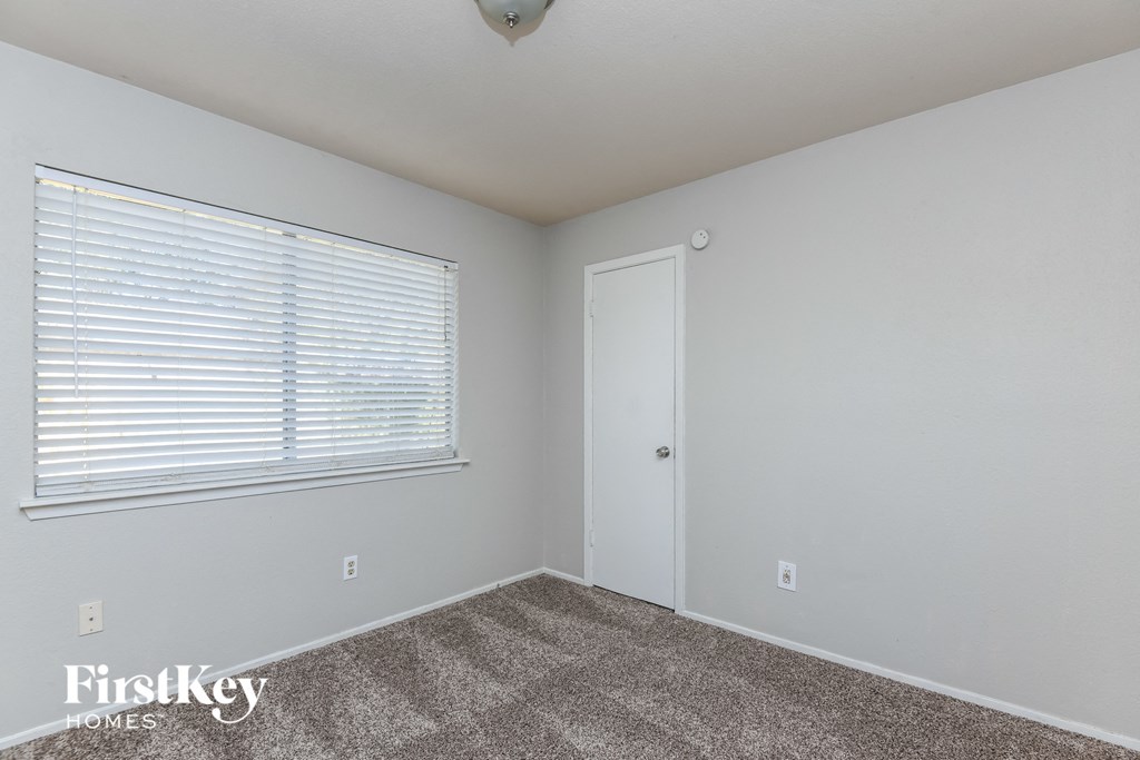 a bedroom with carpet and a window and a door