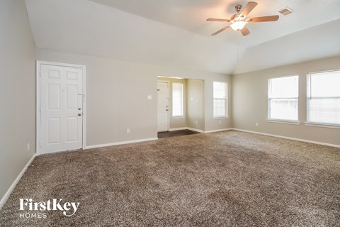 A spacious room with a carpeted floor and a ceiling fan.