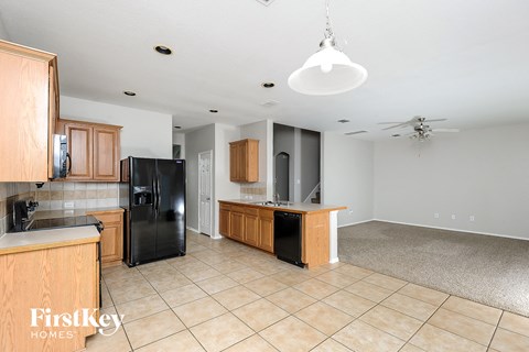 A kitchen with wooden cabinets and a black fridge.