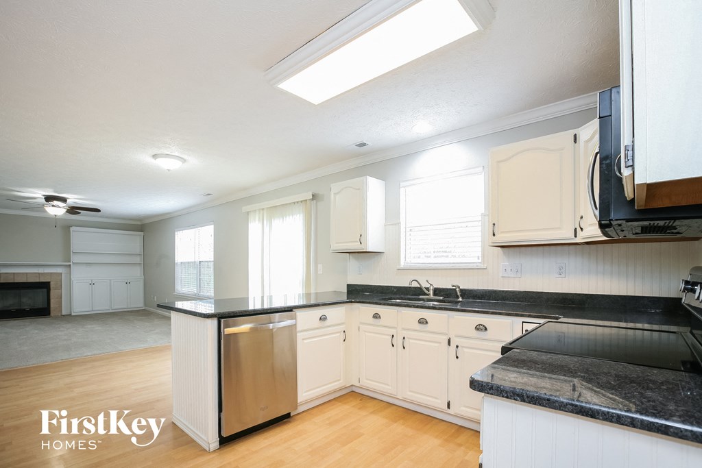 A kitchen with a black counter top and white cabinets.