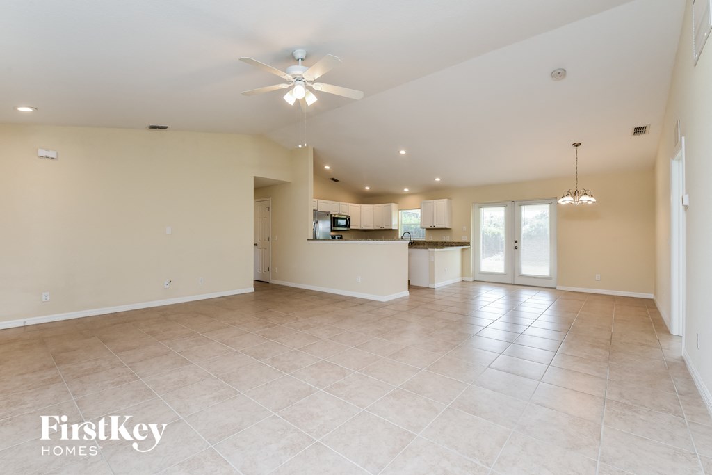 an empty living room and kitchen with a ceiling fan
