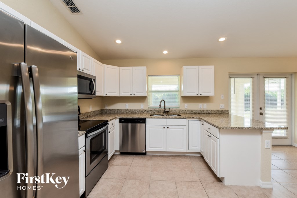 an updated kitchen with stainless steel appliances and white cabinets