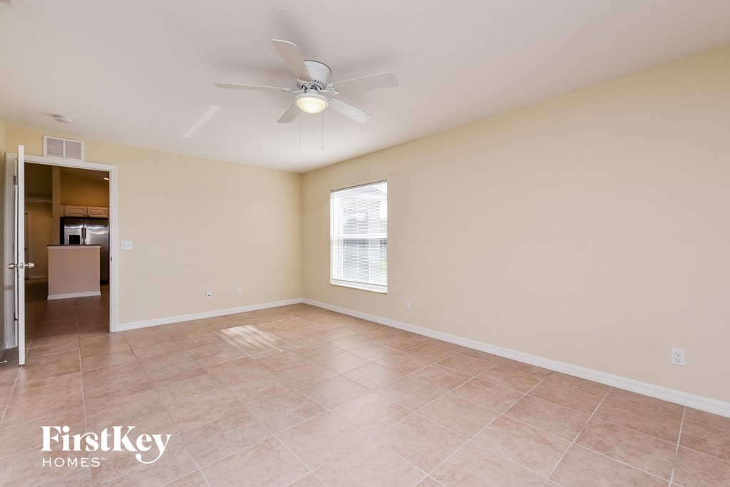 an empty living room with a ceiling fan and tile floor
