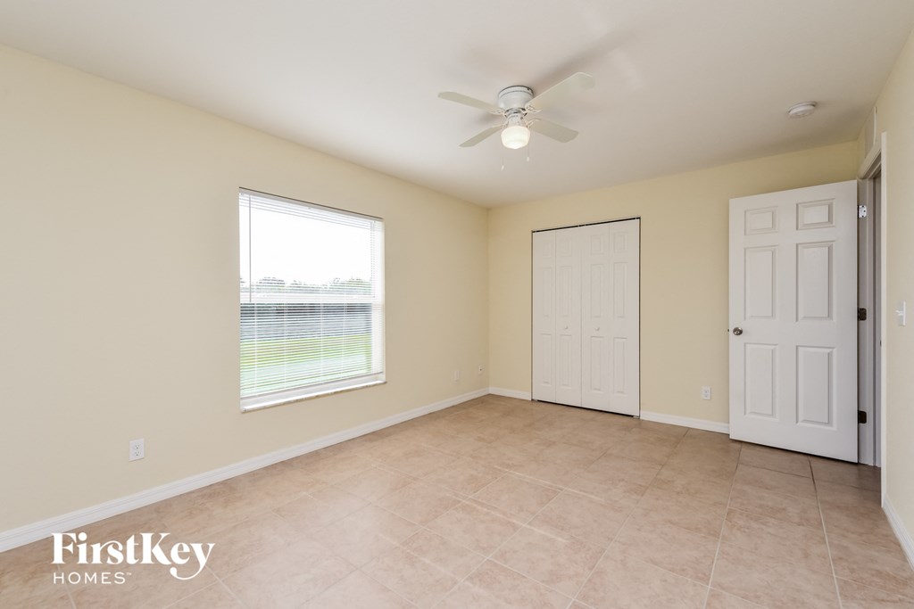 an empty living room with a ceiling fan and a window