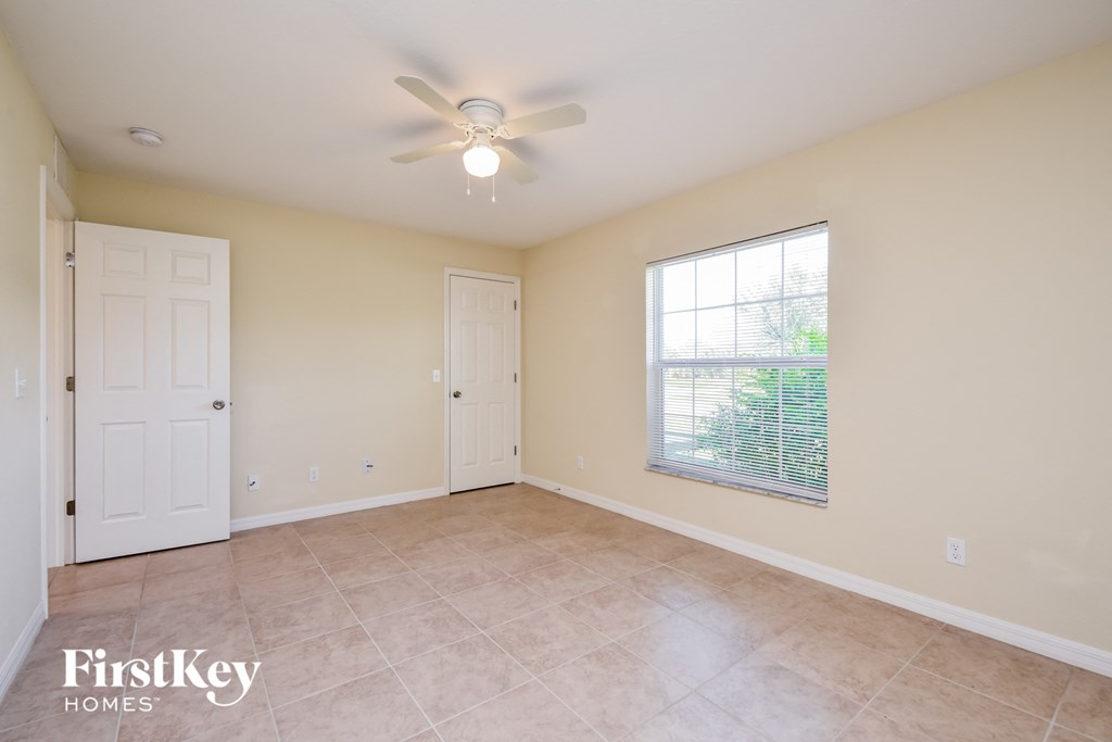 an empty living room with a ceiling fan and a window