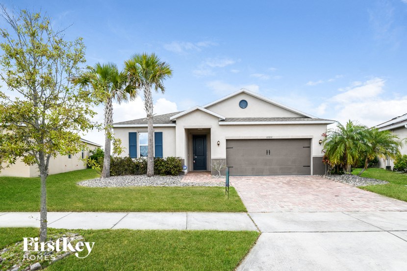 a white house with palm trees and a driveway