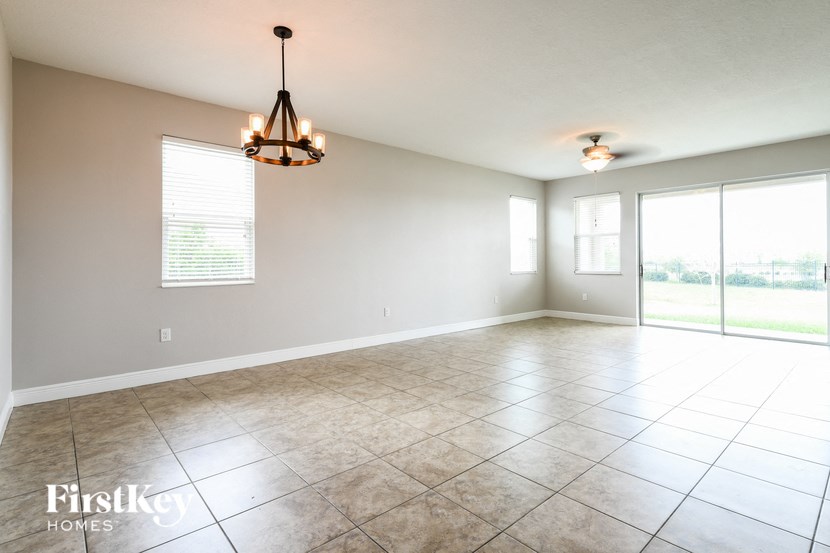 an empty living room with a large window and tile flooring