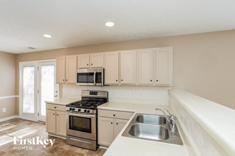 A kitchen with a stove, microwave, and cabinets.