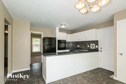 A kitchen with a black refrigerator and white cabinets.