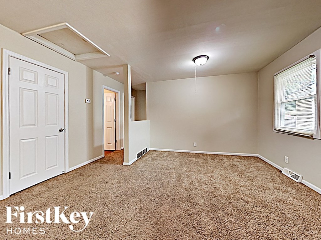 an empty living room with carpet and a white door
