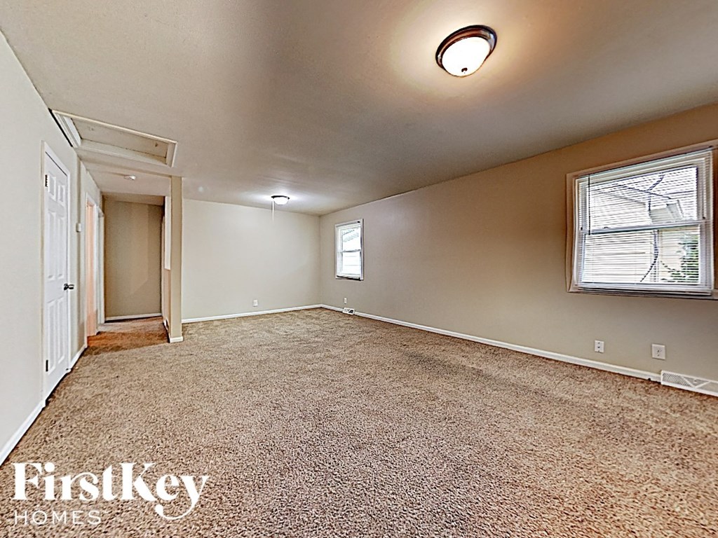 an empty living room with carpet and a door to a closet