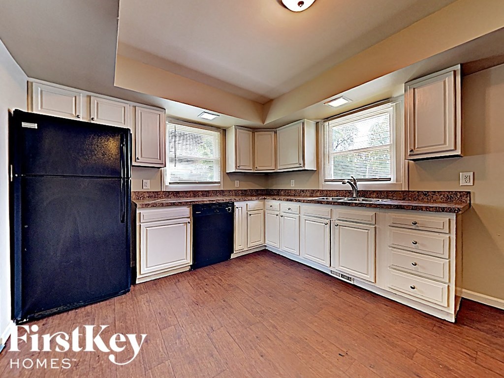 a kitchen with white cabinets and a black refrigerator