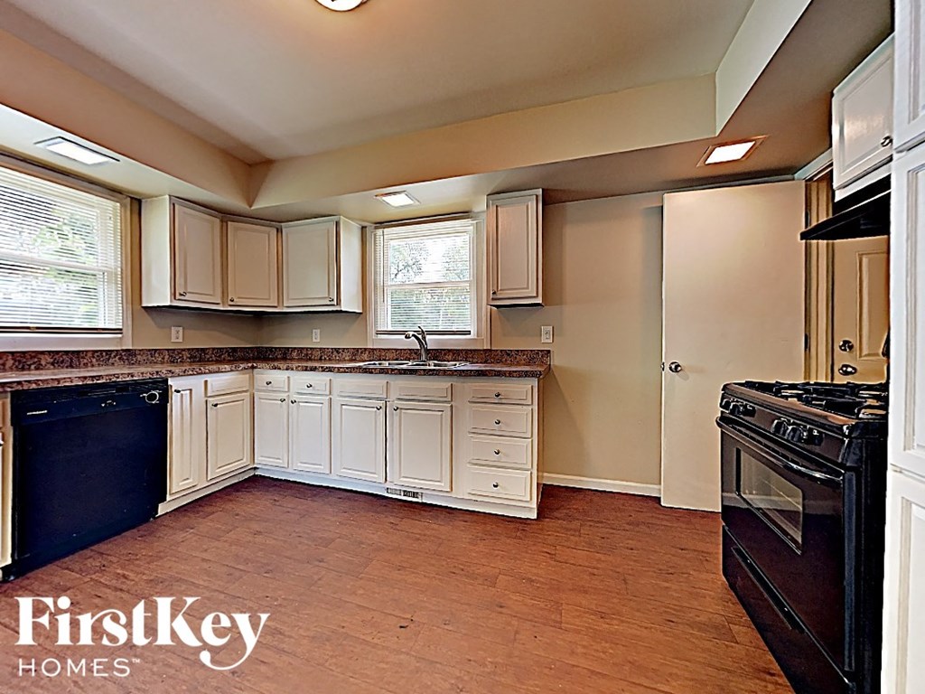 a kitchen with white cabinets and a stove and a sink