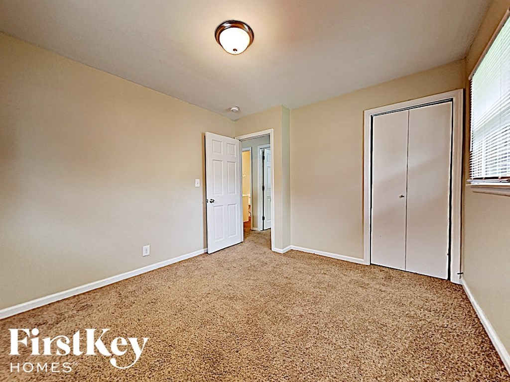 an empty bedroom with a closet and a door to a hallway