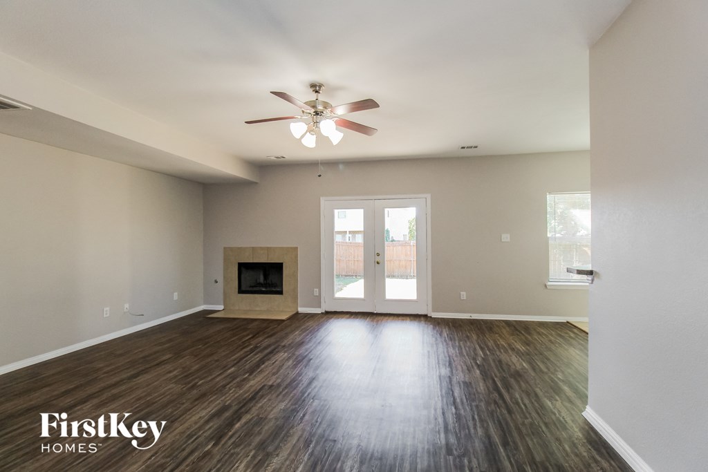 an empty living room with a ceiling fan and a fireplace