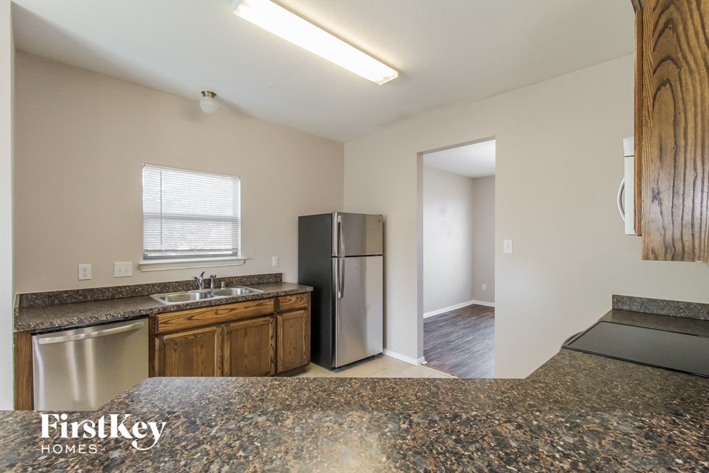 a kitchen with granite counter tops and a stainless steel refrigerator