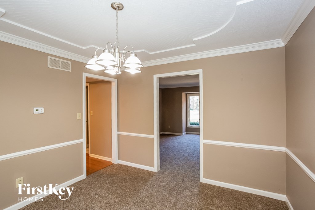 a dining room and hallway with two doors and a chandelier