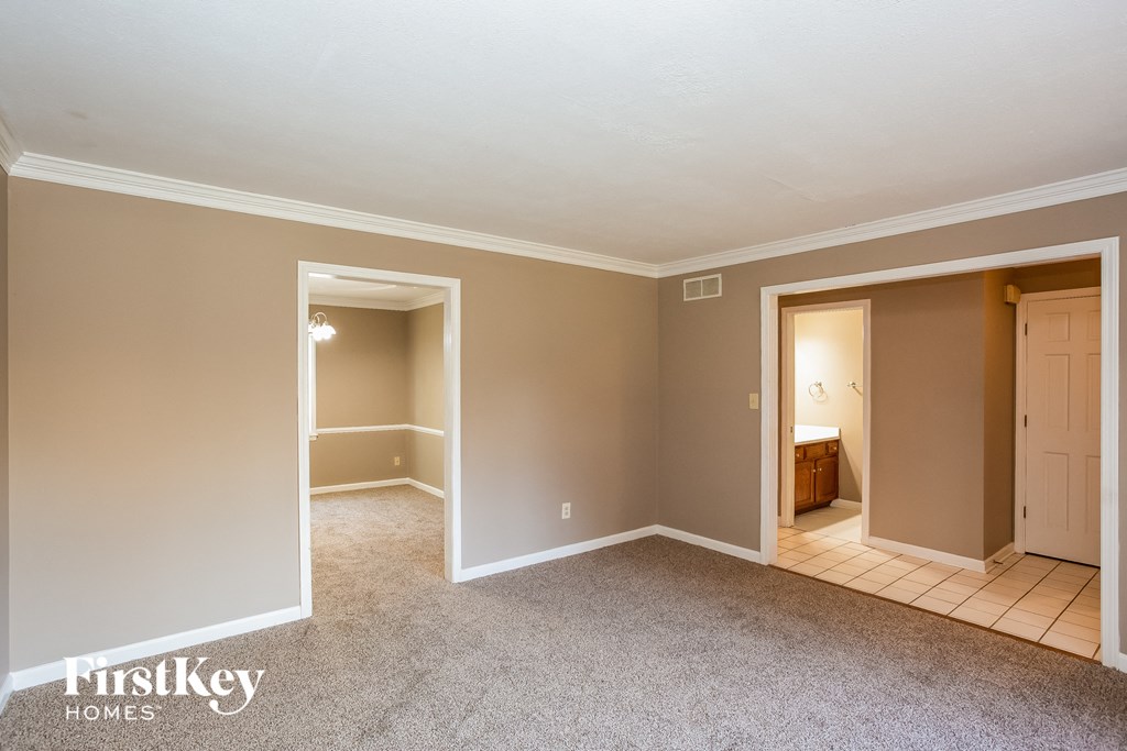 a living room with a carpeted floor and a door to a bathroom