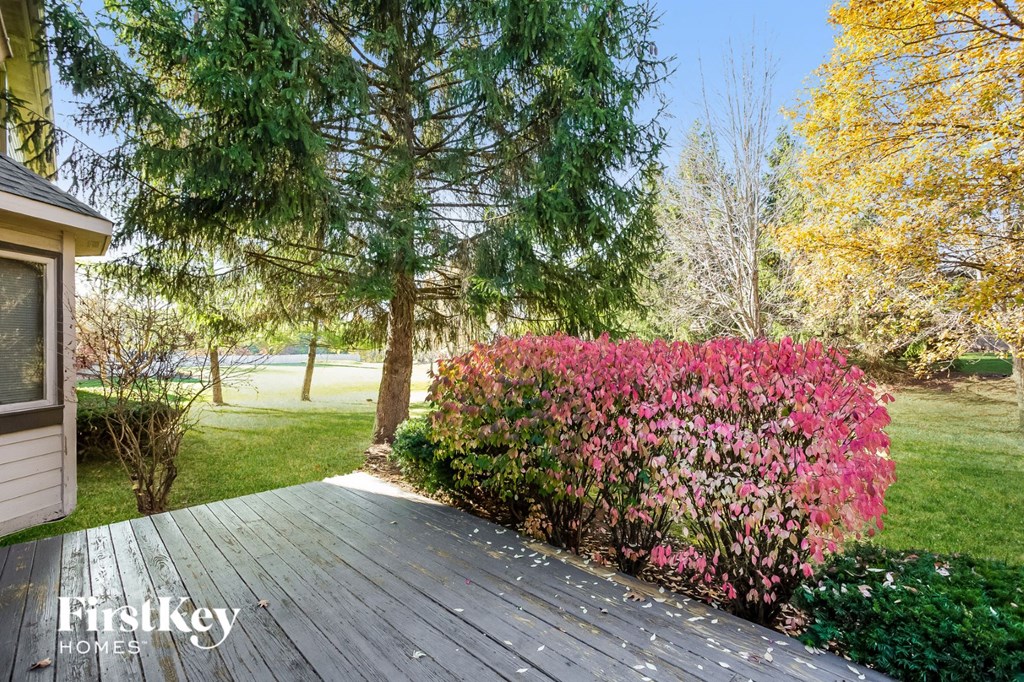 front deck with pink flowers and trees and a lake in the background