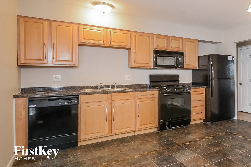 A kitchen with wooden cabinets and black appliances.