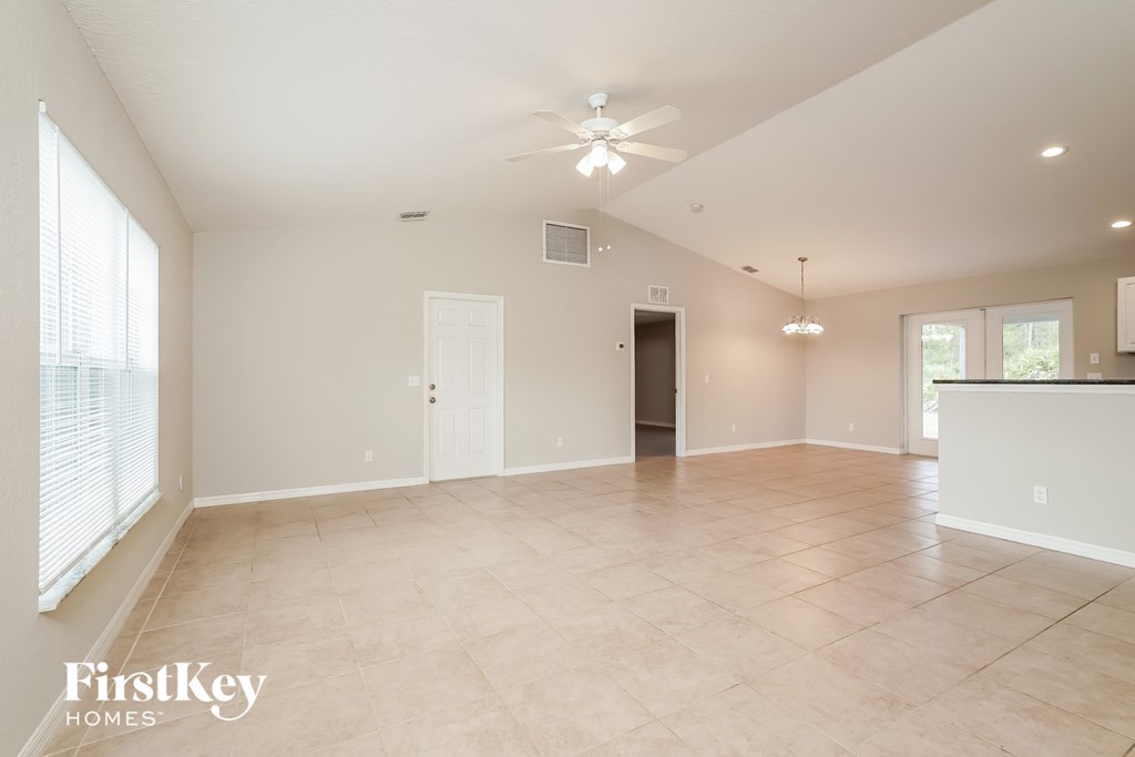 an empty living room with a ceiling fan and a window