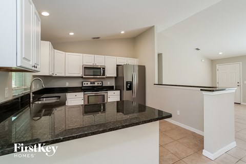 a kitchen with black granite counter tops and white cabinets