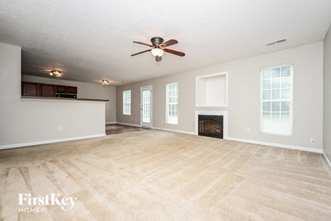 an empty living room with a ceiling fan and a fireplace