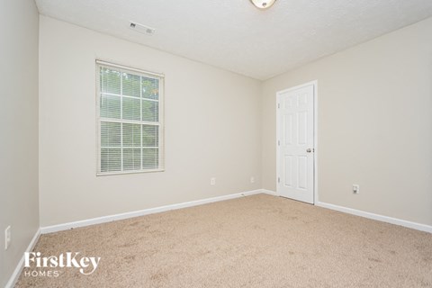 a spacious bedroom with carpet and a door to the bathroom