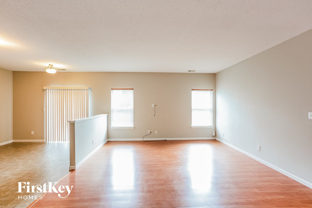 an empty living room with wood floors and white walls