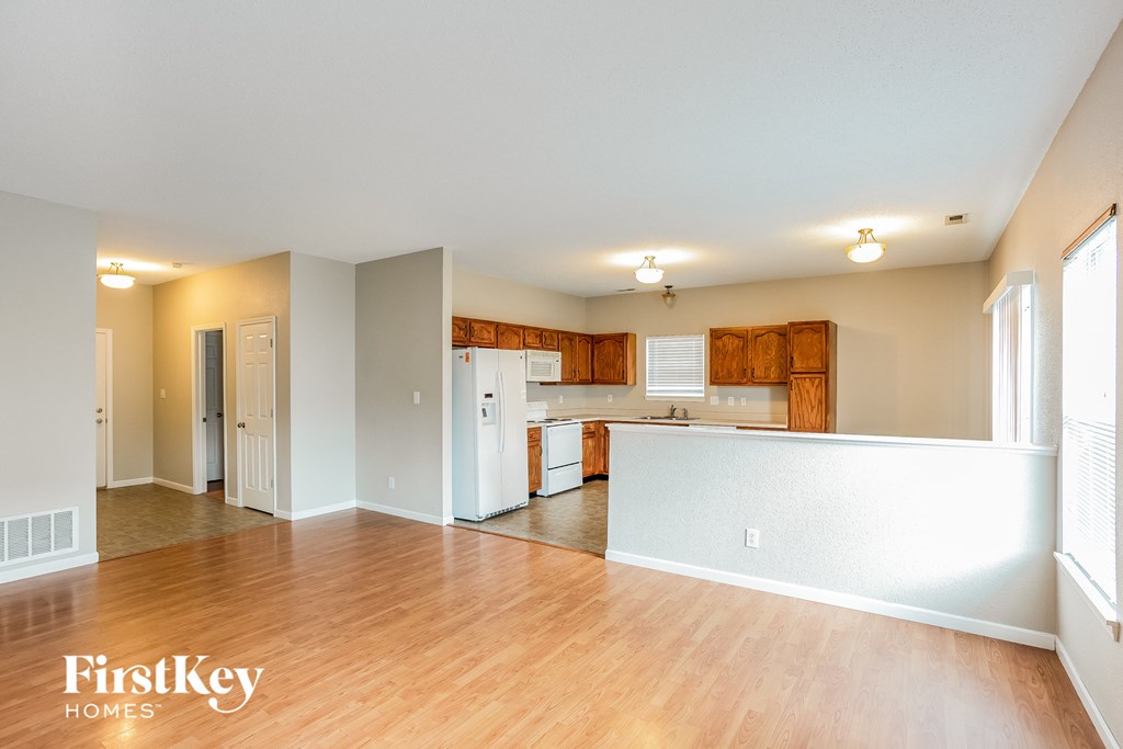 an empty kitchen and living room with wood floors and white appliances
