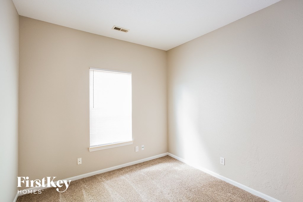 a bedroom with white walls and a window
