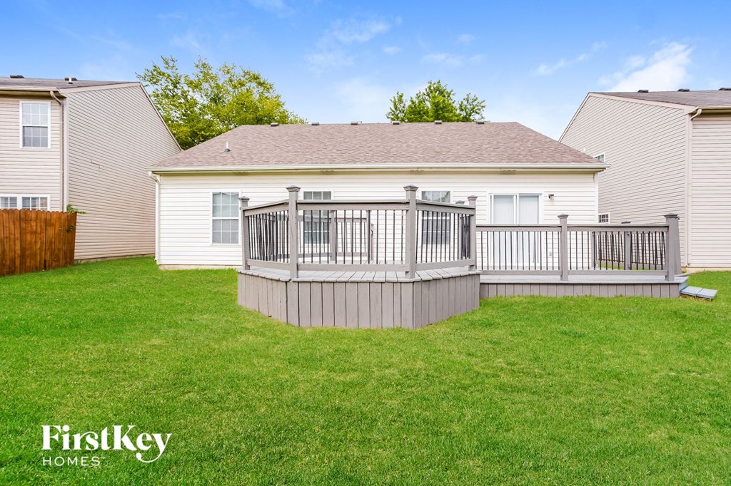 the backyard of a house with a deck and a fence