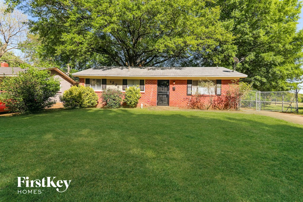 A red brick house with a green lawn in front.