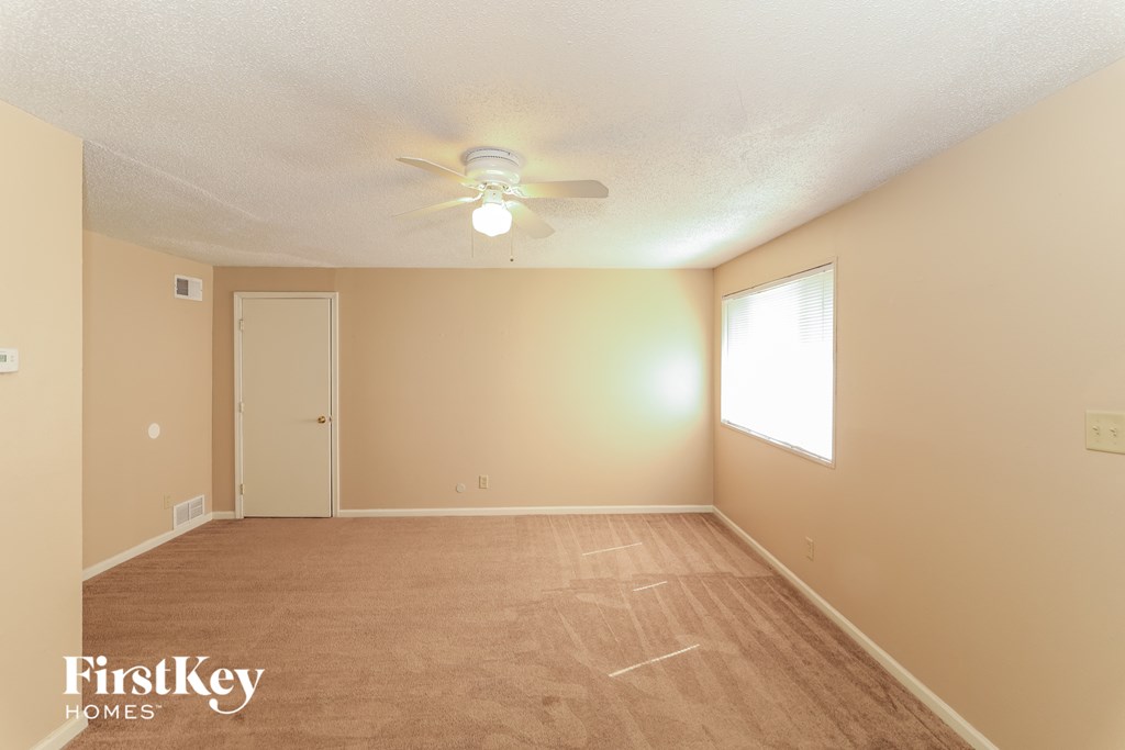 A room with a ceiling fan and a window letting in light.