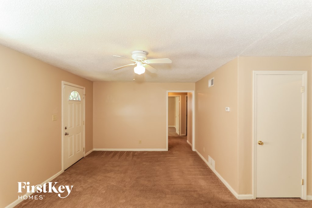 A spacious room with a carpeted floor and a ceiling fan.