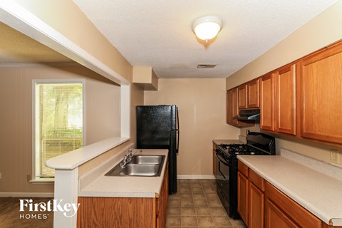 A kitchen with wooden cabinets and a black refrigerator.