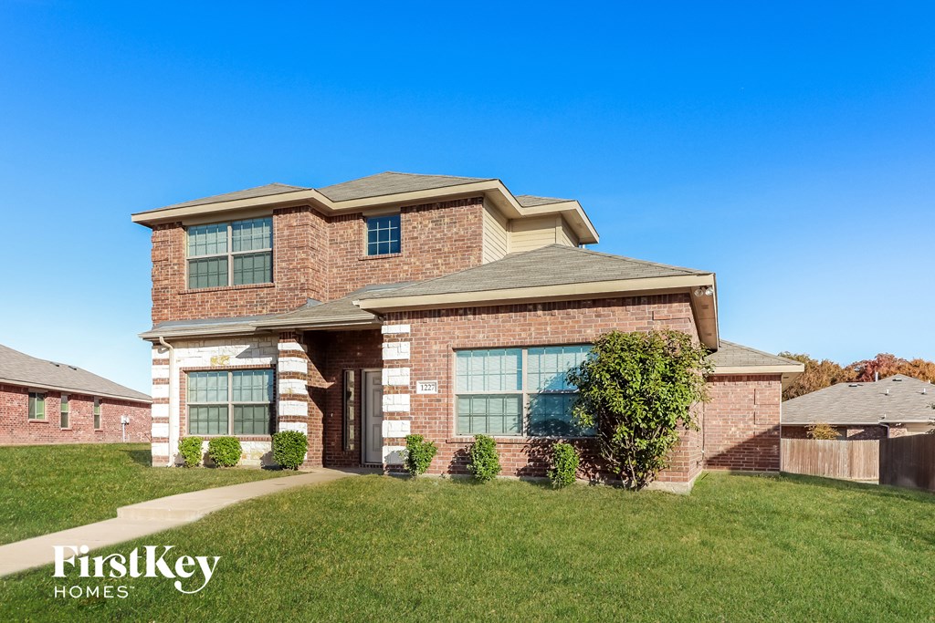 A brick house with a large front yard and a clear blue sky.